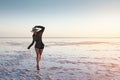 A young Caucasian attractive slender woman is walking along a pink sunlit lake balancing on her toes. Copy space Royalty Free Stock Photo