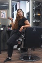 Young caucasian barber woman holding a hair clipper and standing at workplace