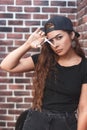 Young caucasian barber woman holding a straight razor and scissors against brick wall