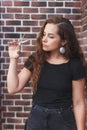 Young caucasian barber woman holding a straight razor and scissors against brick wall