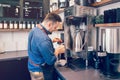 Young Caucasian barista man holding paper cup making coffee using professional machine. Royalty Free Stock Photo