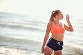 Young caucasian blonde female drinking water from bottle on a beach Royalty Free Stock Photo