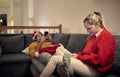 Young caucasian blonde sitting on sofa with her boyfriend laying, both using their cell phones on new year eve. Corona concept Royalty Free Stock Photo