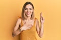 Young caucasian blonde woman wearing casual yellow t shirt smiling swearing with hand on chest and fingers up, making a loyalty Royalty Free Stock Photo