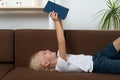 Young caucasian boy with blond hair holding some book on his head and laughs. Happy childhood Royalty Free Stock Photo