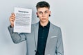 Young caucasian boy with ears dilation holding insurance document thinking attitude and sober expression looking self confident Royalty Free Stock Photo