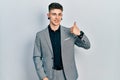 Young caucasian boy with ears dilation wearing business jacket doing happy thumbs up gesture with hand Royalty Free Stock Photo