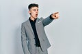 Young caucasian boy with ears dilation wearing business jacket pointing with finger surprised ahead, open mouth amazed expression, Royalty Free Stock Photo