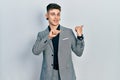 Young caucasian boy with ears dilation wearing business jacket pointing to the back behind with hand and thumbs up, smiling Royalty Free Stock Photo