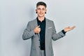 Young caucasian boy with ears dilation wearing business jacket showing palm hand and doing ok gesture with thumbs up, smiling Royalty Free Stock Photo