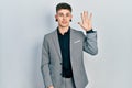 Young caucasian boy with ears dilation wearing business jacket showing and pointing up with fingers number five while smiling Royalty Free Stock Photo