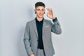 Young caucasian boy with ears dilation wearing business jacket smiling positive doing ok sign with hand and fingers Royalty Free Stock Photo