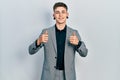 Young caucasian boy with ears dilation wearing business jacket success sign doing positive gesture with hand, thumbs up smiling Royalty Free Stock Photo