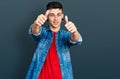 Young caucasian boy with ears dilation wearing casual denim jacket approving doing positive gesture with hand, thumbs up smiling Royalty Free Stock Photo