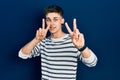 Young caucasian boy with ears dilation wearing casual striped shirt smiling looking to the camera showing fingers doing victory Royalty Free Stock Photo