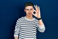 Young caucasian boy with ears dilation wearing casual striped shirt smiling positive doing ok sign with hand and fingers Royalty Free Stock Photo
