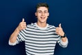 Young caucasian boy with ears dilation wearing casual striped shirt success sign doing positive gesture with hand, thumbs up Royalty Free Stock Photo