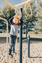 Young Caucasian boy hanging on monkey bars in park on playground. Summer outdoors activity for kids. Active preschool child doing Royalty Free Stock Photo