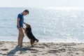 Young caucasian boy playing with dog on beach. Man and dog having fun on seaside Royalty Free Stock Photo