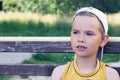 Young Caucasian boy sitting on bench at the park waiting for his friends Royalty Free Stock Photo