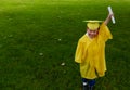 Boy in yellow preschool graduation gown, holding up his diploma