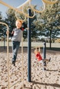 Young Caucasian boys friends hanging on monkey bars and pull-up bars in park on playground. Summer outdoors activity for kids.