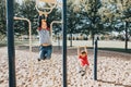 Young Caucasian boys friends hanging on monkey bars and pull-up bars in park on playground. Summer outdoors activity for kids.