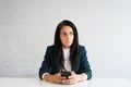 Young caucasian brunette business woman director in office thoughtful entrepreneur hold phone make decisions think before text r Royalty Free Stock Photo