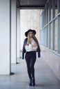 Young Caucasian brunette woman girl in black hat on concrete wall