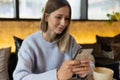 Young Caucasian business woman with blonde hair using mobile phone and social media in cafe. College student using Royalty Free Stock Photo