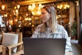 Young Caucasian business woman with blonde hair working on laptop in cafe. College student using technology , online Royalty Free Stock Photo