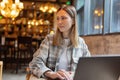 Young Caucasian business woman with blonde hair working on laptop in cafe. College student using technology , online Royalty Free Stock Photo