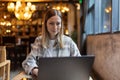 Young Caucasian business woman with blonde hair working on laptop in cafe. College student using technology , online Royalty Free Stock Photo