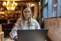 Young Caucasian business woman with blonde hair working on laptop in cafe. College student using technology , online Royalty Free Stock Photo