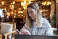 Young Caucasian business woman with blonde hair working on laptop in cafe. College student using technology , online Royalty Free Stock Photo