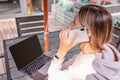 Young Caucasian business woman with blonde hair working on laptop in outdoor cafe. College student using technology Royalty Free Stock Photo