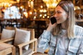 Young Caucasian business woman with blonde hair working on mobile phone in cafe. College student using technology Royalty Free Stock Photo