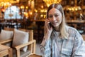 Young Caucasian business woman with blonde hair working on mobile phone in cafe. College student using technology Royalty Free Stock Photo