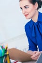 Young smiling business woman in jacket write on clipboard at the workplace in the office. Royalty Free Stock Photo