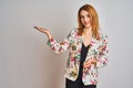 Young caucasian business woman wearing spring floral jacket suit over isolated background smiling cheerful presenting and pointing