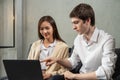 Young caucasian businessman and businesswoman work together, look at computer, man point to laptop, selective focus at man. Royalty Free Stock Photo