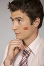 Young caucasian businessman with lipstick kiss mark on his cheek