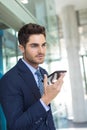 Young Caucasian businessman speaking on mobile phone while standing in modern office Royalty Free Stock Photo