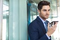 Young Caucasian businessman speaking on mobile phone while standing in modern office Royalty Free Stock Photo