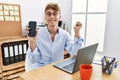 Young caucasian businessman working using laptop and showing smartphone screaming proud, celebrating victory and success very Royalty Free Stock Photo