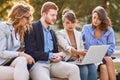 Young caucasian businesswoman showing content on laptop to her colleagues at bench in park. serious, worried businesspeople after Royalty Free Stock Photo