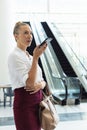 Young Caucasian businesswoman speaking on mobile phone while standing in modern office Royalty Free Stock Photo