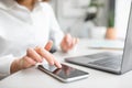 Young caucasian businesswoman using smartphone with blank screen at table with laptop in office, selective focus Royalty Free Stock Photo