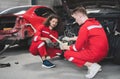 Young Caucasian car mechanic with a checklist, Mechanics in uniform are working in auto service, Technician checking modern car at Royalty Free Stock Photo