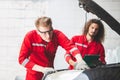 Young Caucasian car mechanic with a checklist, Mechanics in uniform are working in auto service, Technician checking modern car at Royalty Free Stock Photo